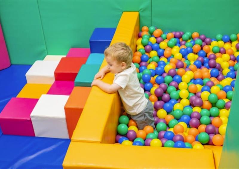 A toddler smiling in a colourful ball pool
